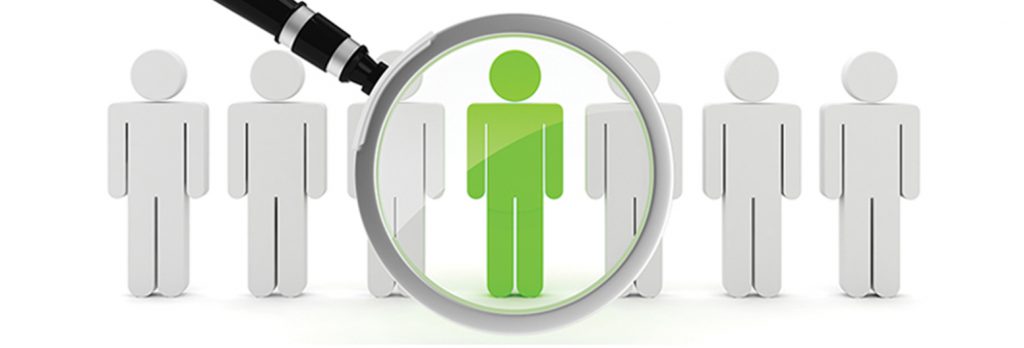 Human stick figures in a line with one green one that has a magnifying glass over it