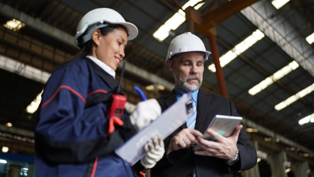 Factory manager or businessman and female plastic engineer collaborating happily in a factory setting.