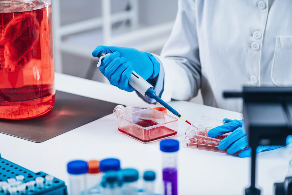 Biotechnology researcher in laboratory working with plastic containers containing cell culture. An example of recruitment in the Field of Medical Plastics