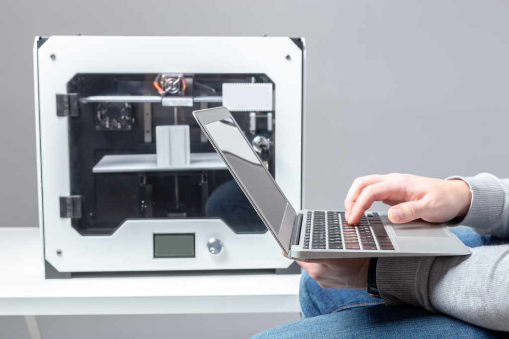 An example of plastic technology engineering and how it is shaping the future of the plastics industry. A polymer engineer working on his laptop beside a 3-D printing.