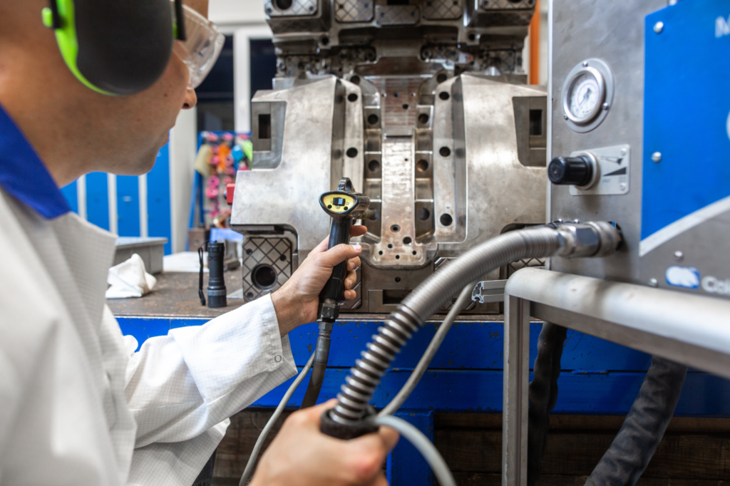 Plastics engineer working on a plastics injection molding machine in a manufacturing plant