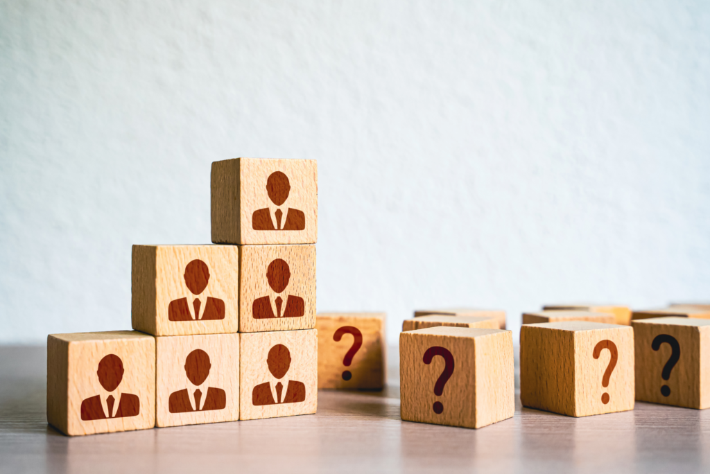 A photo of plastics worker building blocks stacked on top of one another and blocks with question marks beside them toppled over to represent the Plastics Industry Struggles to Deal with Labor Shortages