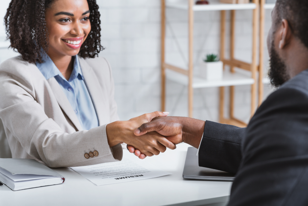 A woman and man shaking hands in a professional setting to represent how to successfully hire a sales manager by managing the Evolving Dynamics of the Plastics Industry